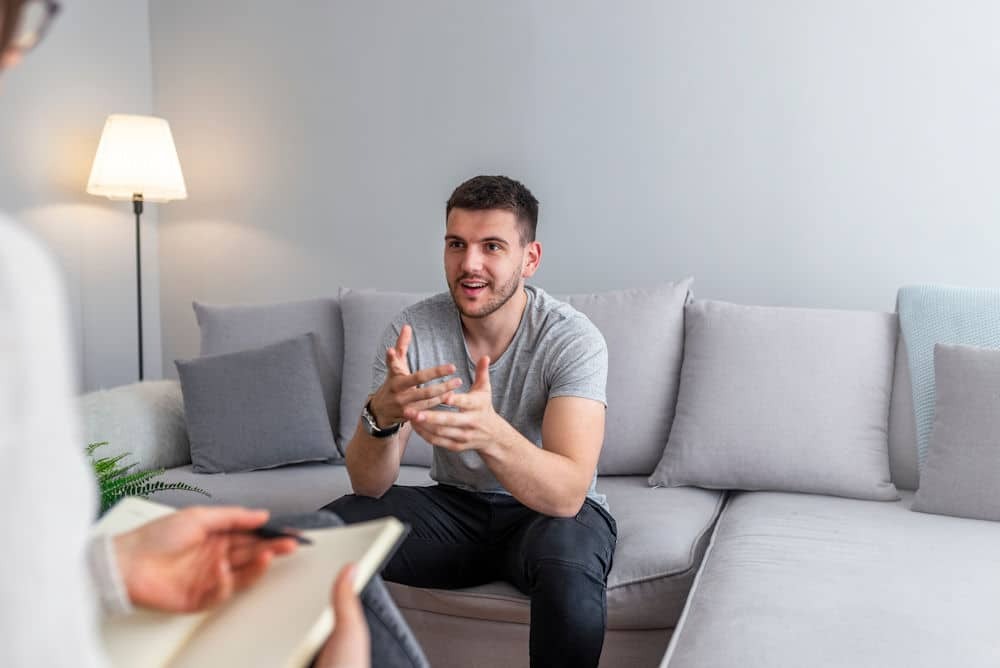 man sitting on couch talking to a therapist