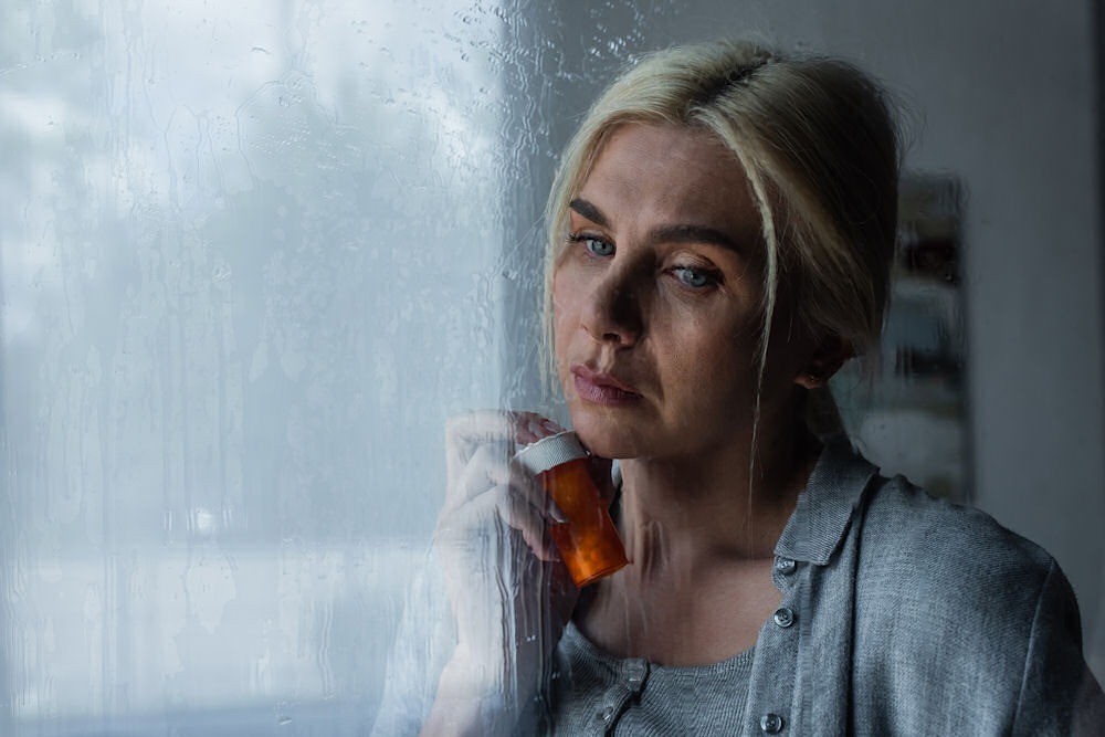 woman-holding-pill-bottle-on-window