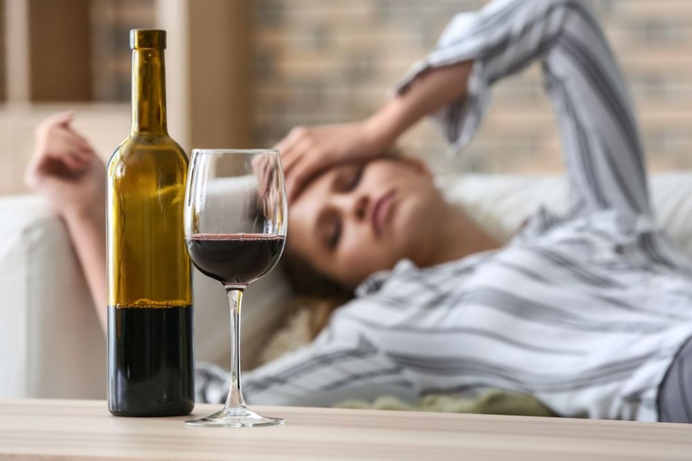 a woman with hand on head and wine on table