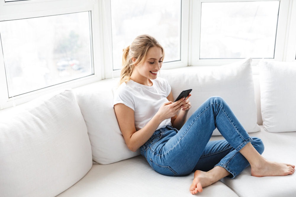 a woman smiling on her cell phone on couch